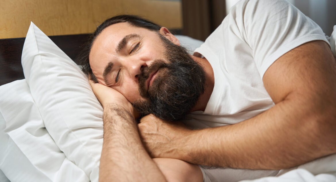 Bearded man sleeps in a bright hotel room, the room is clean and comfortable