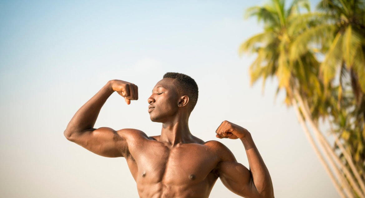 Man flexing arm muscles on beach