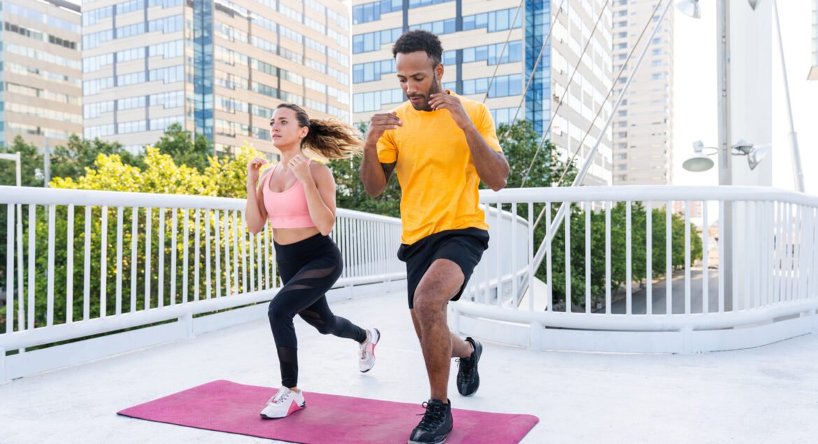 Interracial sportive couple training outdoors - Multiracial couple wearing sportswear and doing functional workout outdoors to strenght body muscles, core abs, stamina and cardio