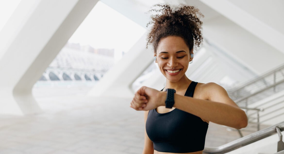 Young woman in sportswear looking at smartwatch and counting calories burned. Healthy life concept
