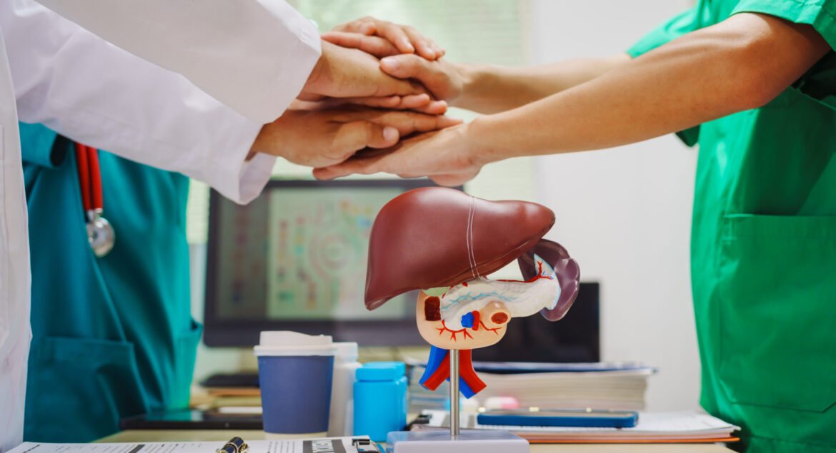 Three doctors join hands at a hospital table after meeting on liver disease,discussing conditions