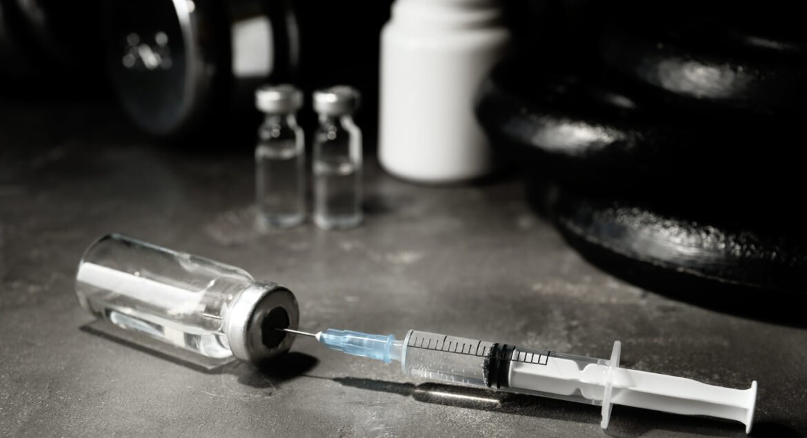 Vial and syringe with drug near sports equipment on grey table. Doping control