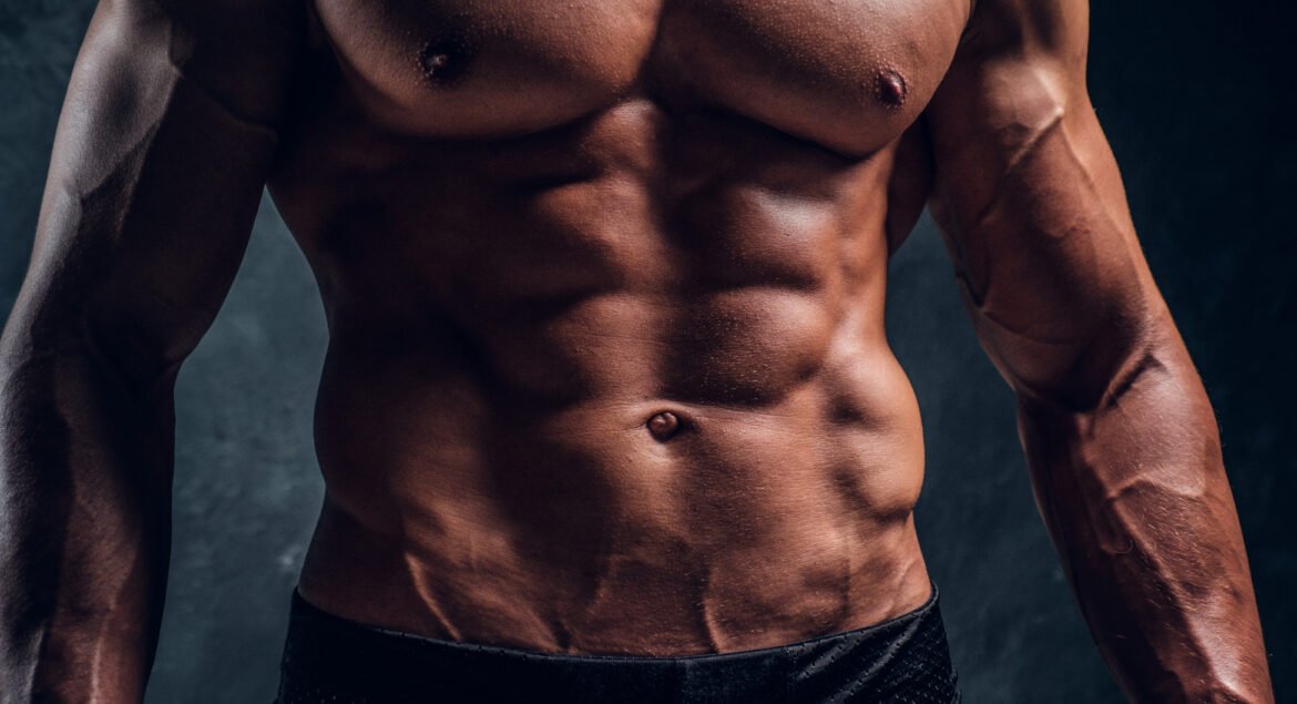 Naked ahletic man with muscular body. Close-up image of torso with dark wall background