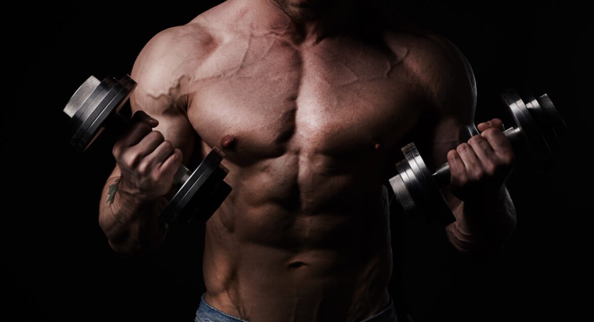 Handsome athletic man bodybuilder doing exercises with dumbbells